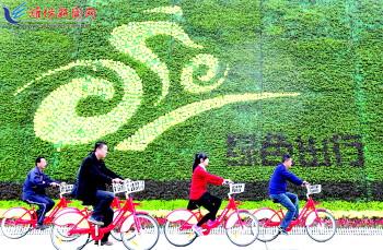 市民騎公共自行車路過市人民廣場(chǎng)一處花壇。記者 張馳